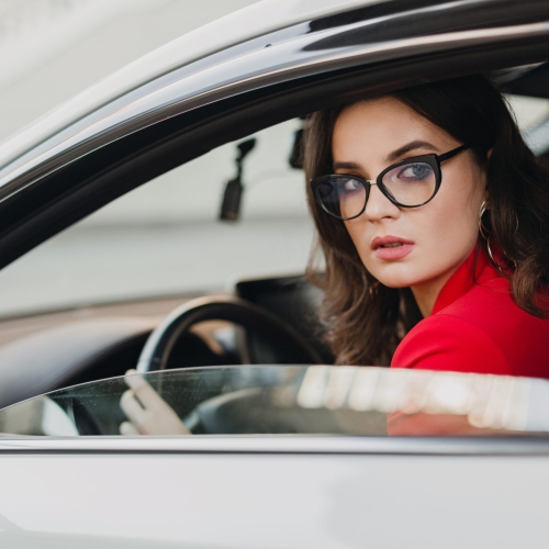 beautiful sexy rich business woman in red suit sitting in white car, wearing glasses