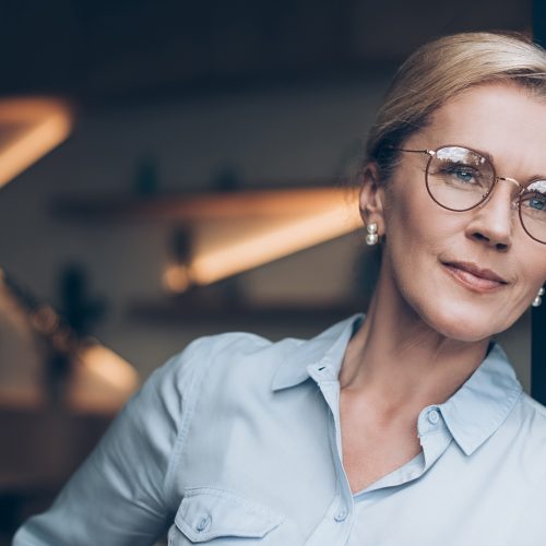 portrait of pensive woman in eyeglasses looking away